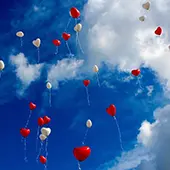 red and white balloons float in a blue sky